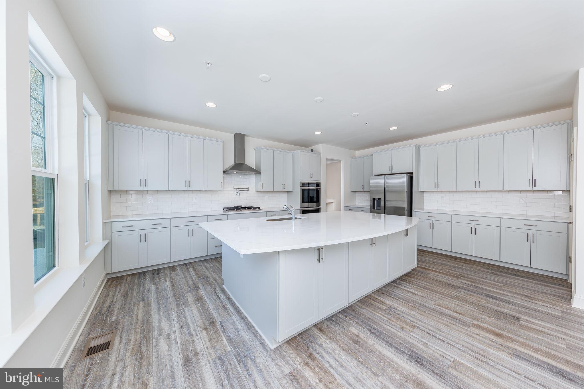 15719 Henrietta Drive Accokeek, MD 20607 - Photo 31 of 48 a large white kitchen with kitchen island a sink dishwasher a stove a refrigerator with white cabinets and wooden floor