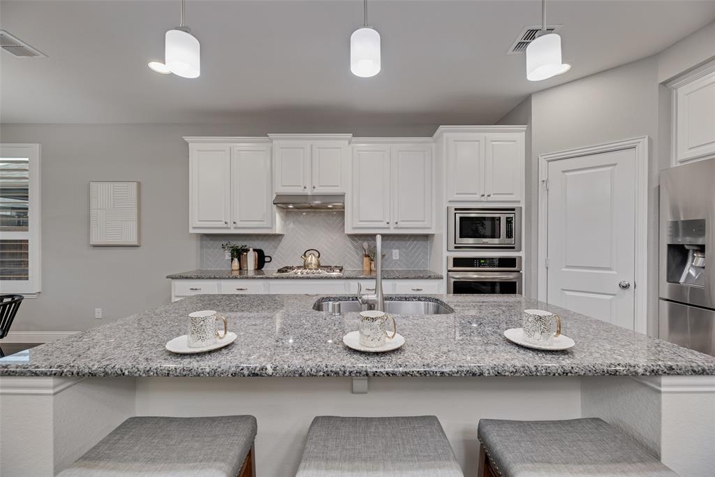 1508 Cherry Blossom Lane Prosper, TX 75078 - Photo 10 of 40 a kitchen with granite countertop a white cabinets and wooden floor