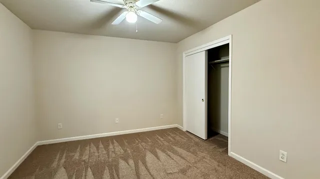 an empty room with a ceiling fan and carpet