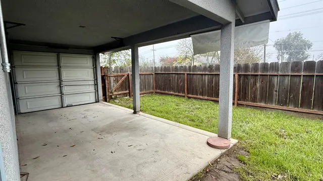 a view of a backyard with a large tree and wooden fence