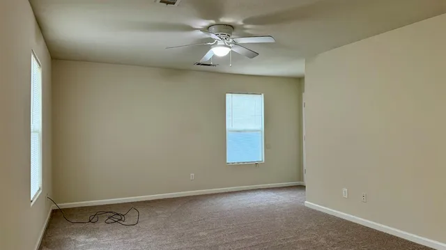 an empty room with windows and fan