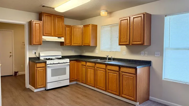 a kitchen with stainless steel appliances granite countertop a stove a sink and a microwave