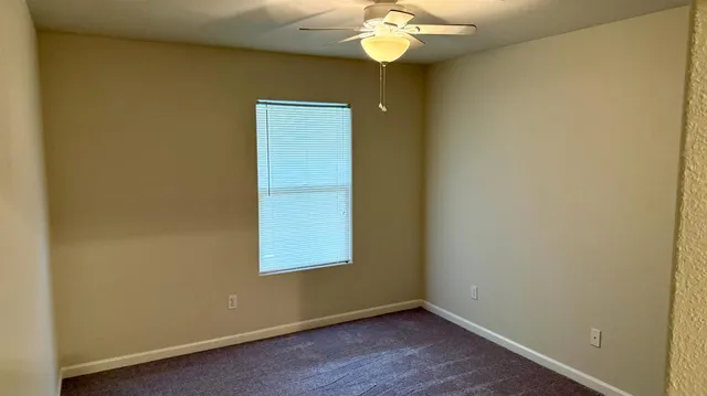 an empty room with a chandelier fan and a window