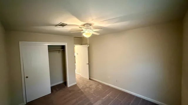 an empty room with wooden floor and fan