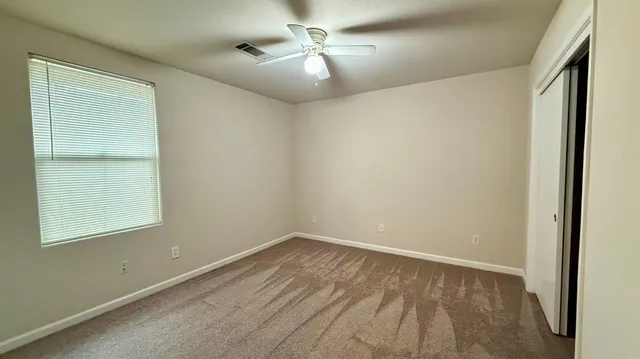 an empty room with a window and a fan
