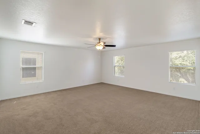 an empty room with windows and chandelier fan