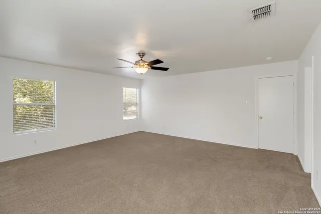 an empty room with windows and chandelier fan
