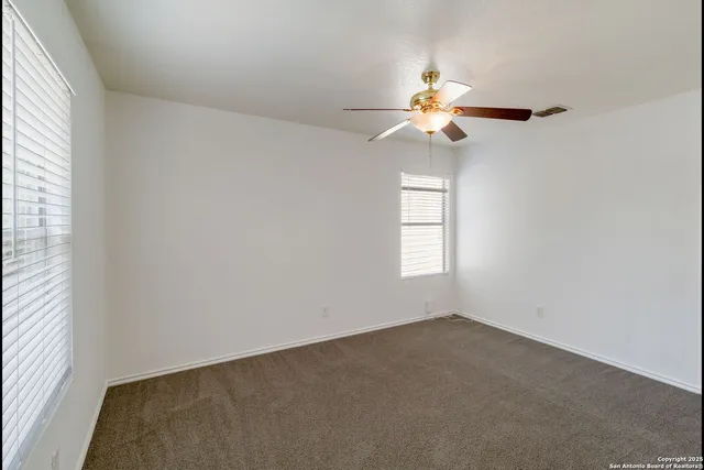 an empty room with windows and fan