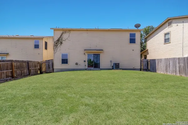 a view of a house with backyard and wooden fence