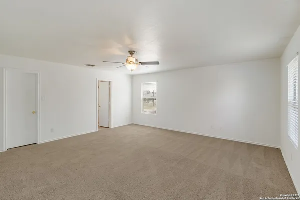 a view of an empty room with a chandelier fan