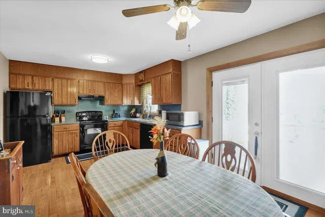 a kitchen with stainless steel appliances granite countertop a refrigerator a stove a sink a dining table and chairs with wooden floor