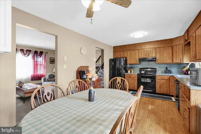 a kitchen with stainless steel appliances kitchen island granite countertop a refrigerator a stove a sink dishwasher a dining table and chairs with wooden floor