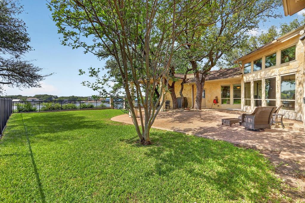 8877 Random Road Fort Worth, TX 76179 - Photo 29 of 40 Expansive outdoor living area featuring a stone patio, manicured lawn, and mature trees