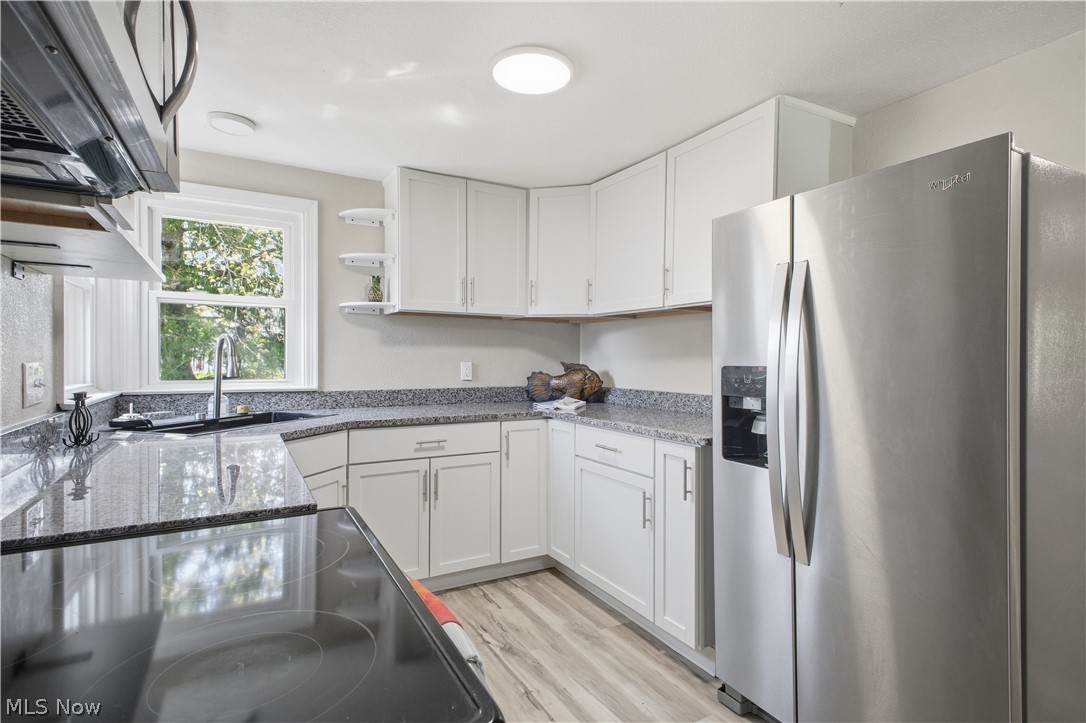3232 Bears Den Road Youngstown, OH 44511 - Photo 6 of 38 Kitchen featuring white cabinetry, dark speckled countertops, stainless steel refrigerator, black electric range, and wood-finish flooring