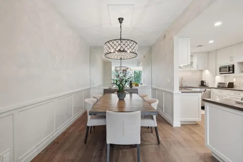 a kitchen with stainless steel appliances granite countertop a dining table chairs and white cabinets