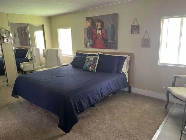 a large bed sitting in a bedroom next to a window with painting on the wall