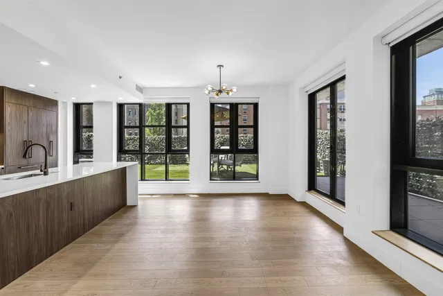 a large white kitchen with large windows and refrigerator