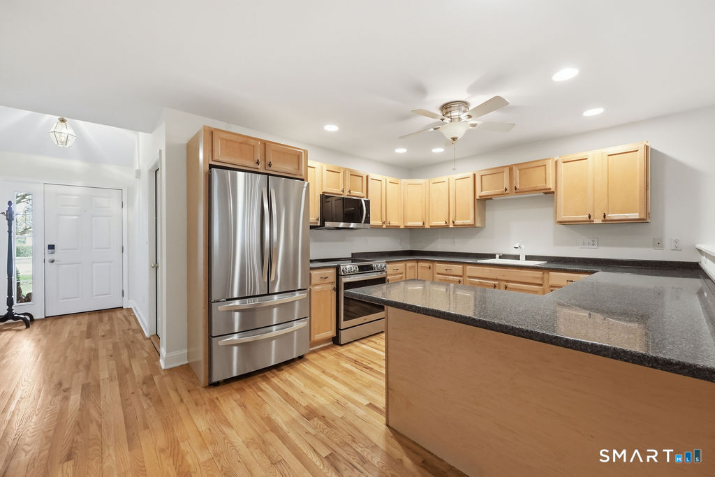 98 Haley Lane, Unit 98 Newtown, CT 06482 - Photo 14 of 33 a kitchen with stainless steel appliances granite countertop a refrigerator a sink dishwasher a stove and white countertops with wooden floor
