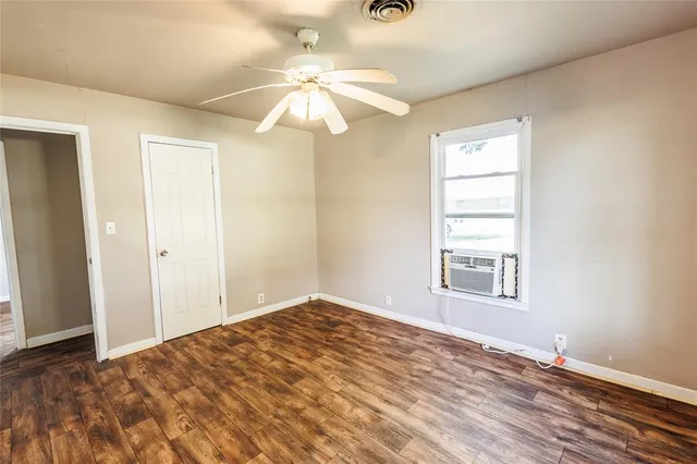 an empty room with windows and chandelier fan