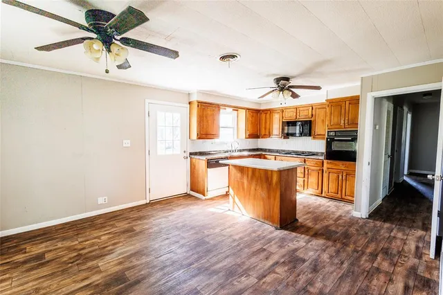 a large kitchen with stainless steel appliances kitchen island granite countertop a stove a refrigerator a sink a dining table and chairs with wooden floor