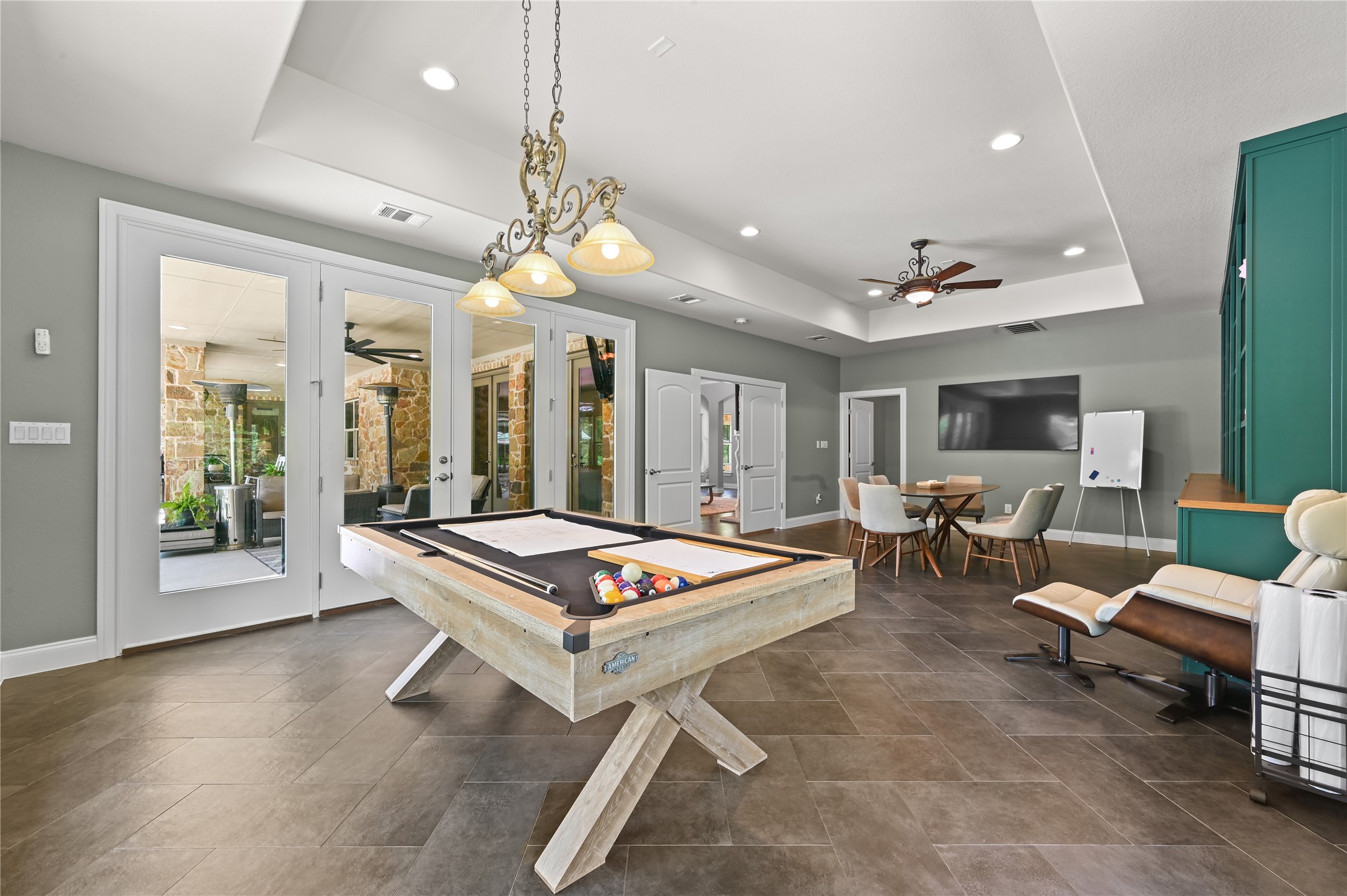 387 Corral Road Smithville, TX 78957 - Photo 24 of 40 Spacious recreational room featuring a tray ceiling with recessed lighting, an ornate chandelier, and French doors leading to an outdoor patio