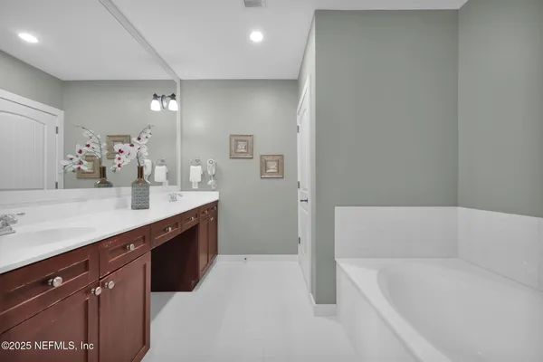 a bathroom with a tub sink and mirror