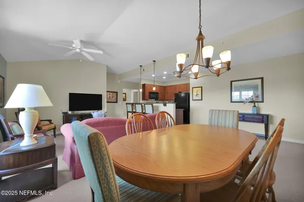 a open kitchen with stainless steel appliances kitchen island granite countertop a refrigerator a stove a sink a dining table and chairs with wooden floor