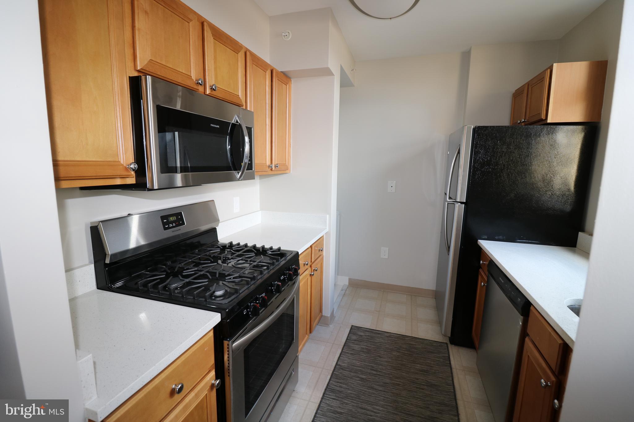 7111 Woodmont Avenue, Unit 415 Bethesda, MD 20815 - Photo 5 of 10 a kitchen with stainless steel appliances a stove microwave and sink