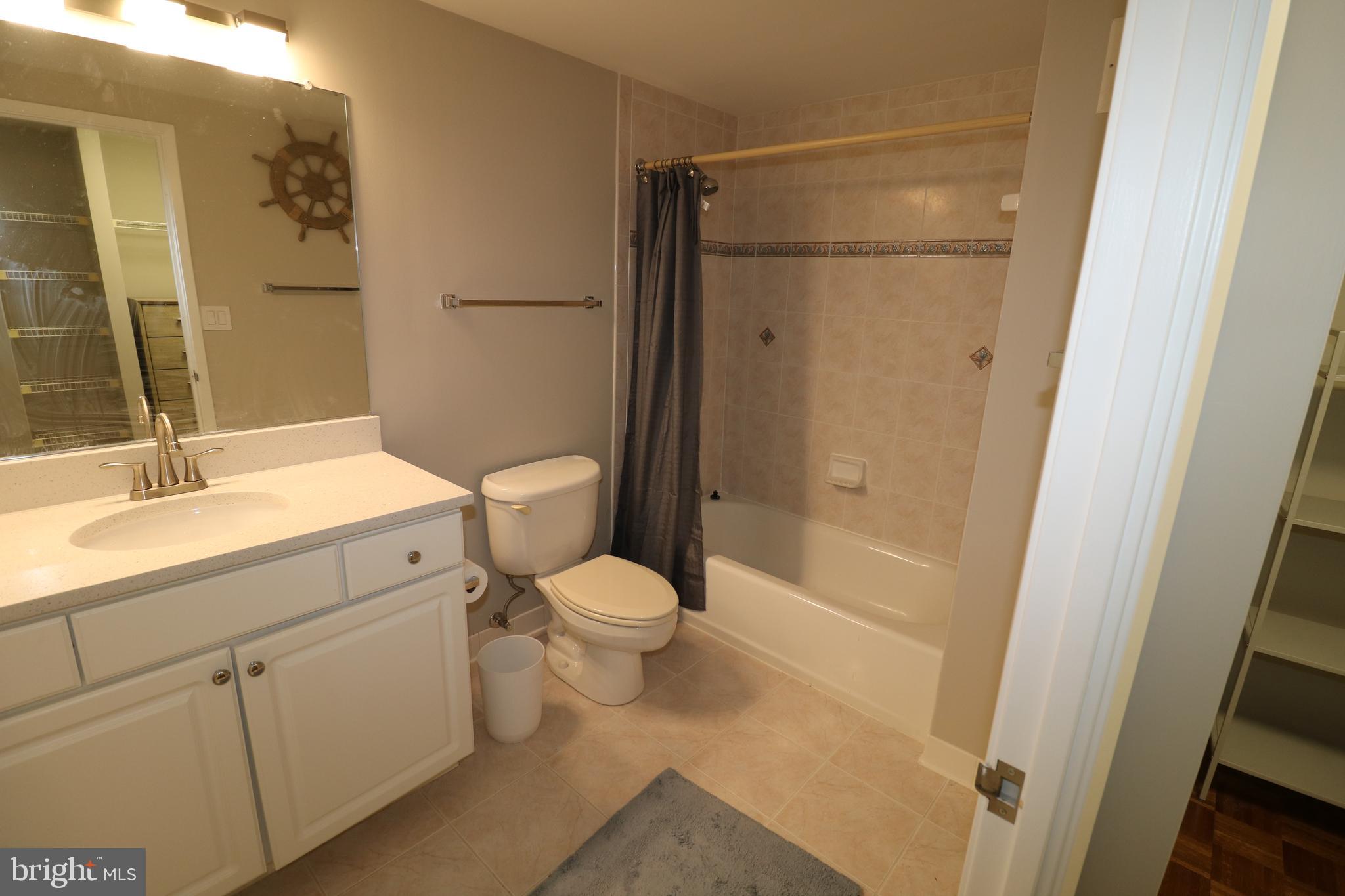 7111 Woodmont Avenue, Unit 415 Bethesda, MD 20815 - Photo 6 of 10 a bathroom with a granite countertop sink toilet and shower