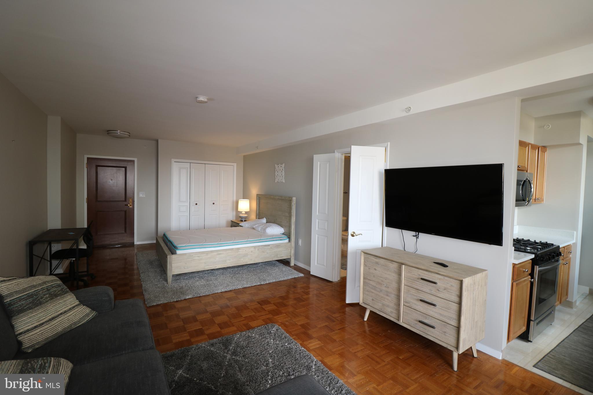 7111 Woodmont Avenue, Unit 415 Bethesda, MD 20815 - Photo 8 of 10 a living room with furniture and a flat screen tv