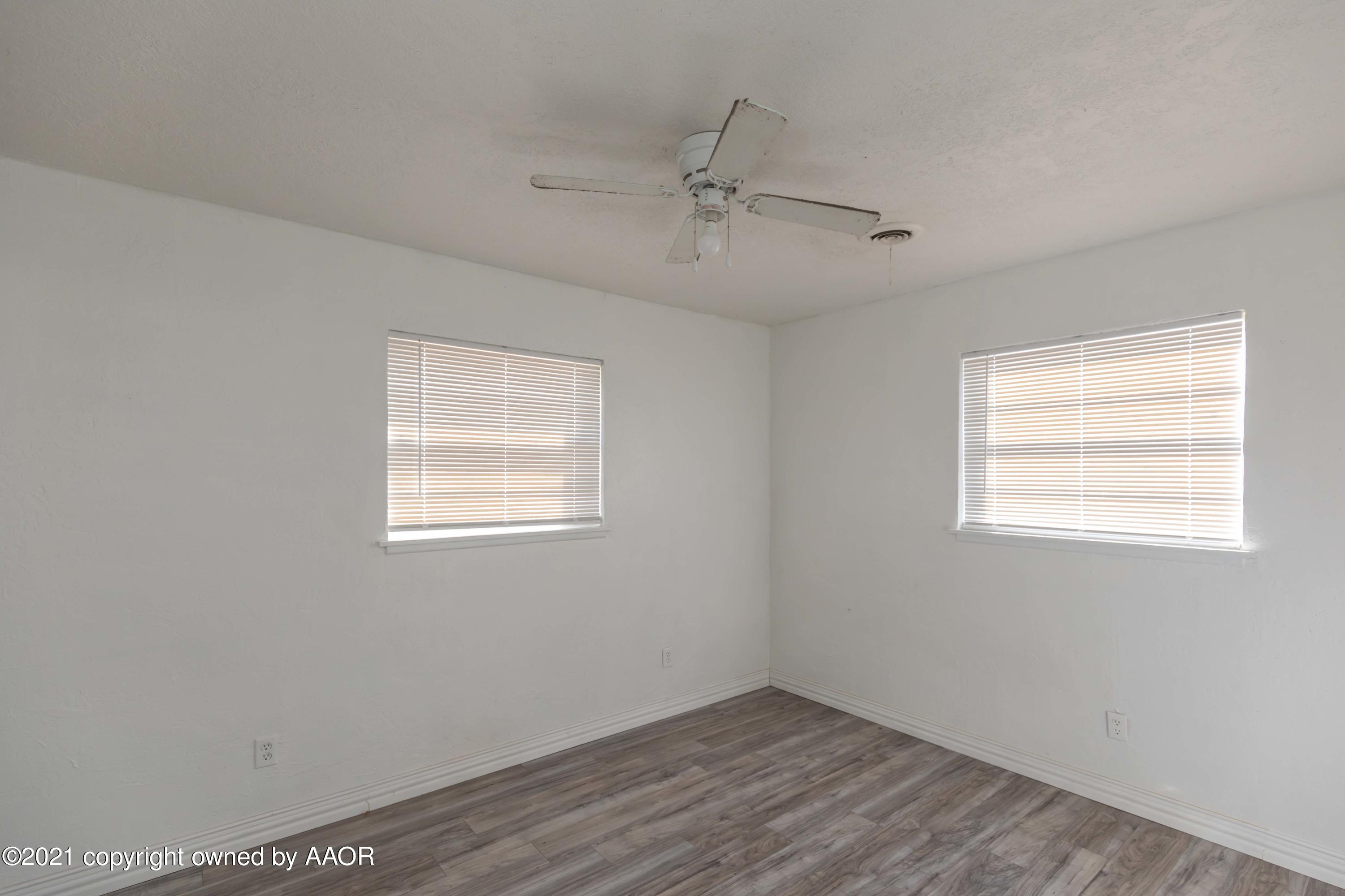 5102 South Travis Street Amarillo, TX 79110 - Photo 21 of 24 an empty room with wooden floor ceiling fan and windows