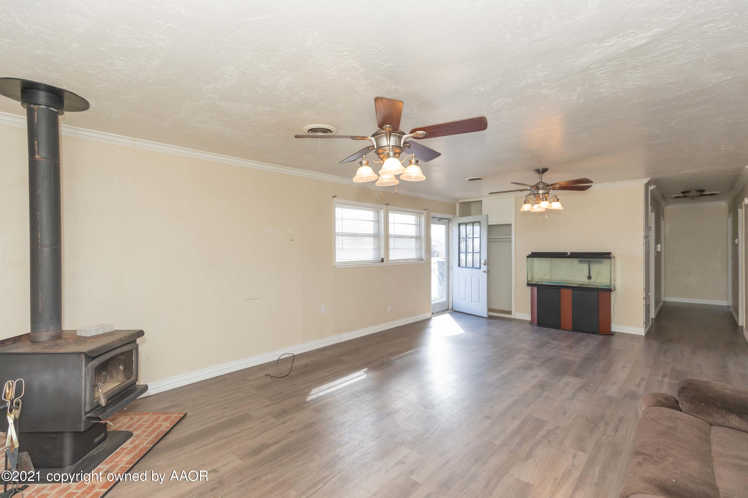 5102 South Travis Street Amarillo, TX 79110 - Photo 5 of 24 an empty room with wooden floor a kitchen view and a window