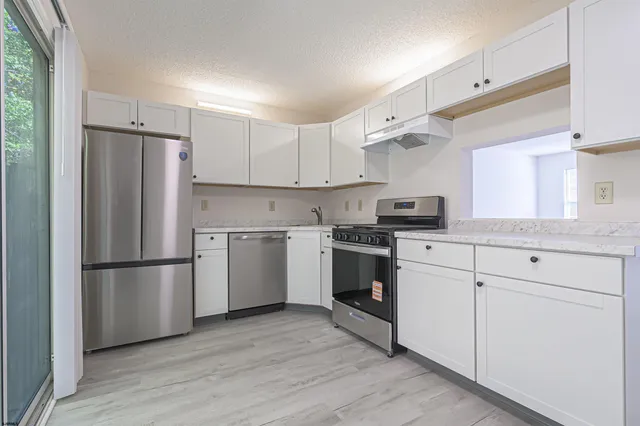 a kitchen with white cabinets stainless steel appliances and a refrigerator