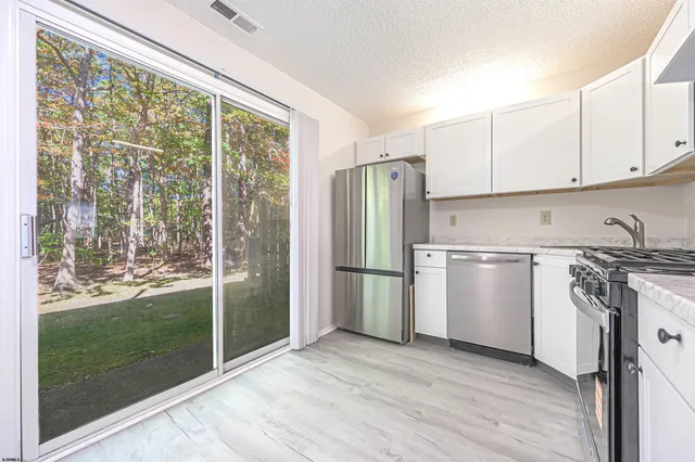 a kitchen with a refrigerator a stove top oven and white cabinets