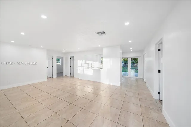 a view of an empty room and a kitchen