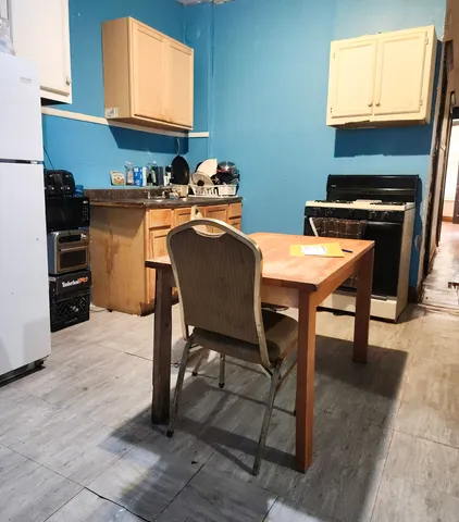 a kitchen with stainless steel appliances granite countertop a stove top oven a sink a dining table and chairs with wooden floor