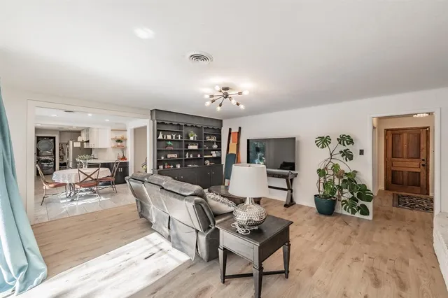 a living room with furniture a dining table with rug potted plant and couches
