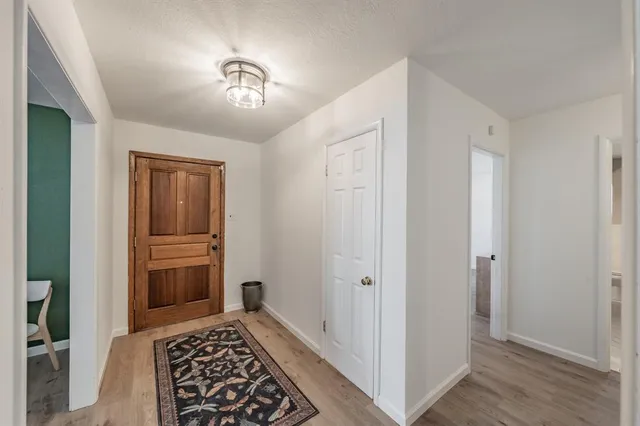 a view of a hallway with wooden floor and a bathroom