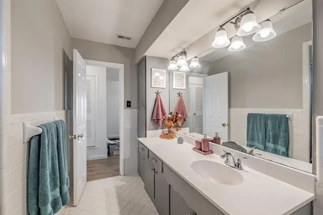 a bathroom with double vanity sinks a vanity a lamp and a mirror
