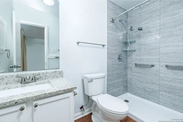 a bathroom with a granite countertop sink toilet and shower
