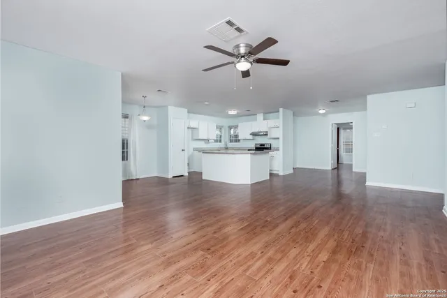 a view of a kitchen with a wooden floor and a ceiling fan