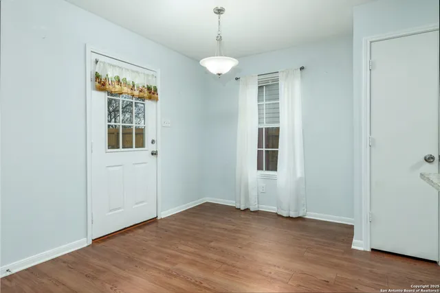 a view of an empty room with wooden floor and windows
