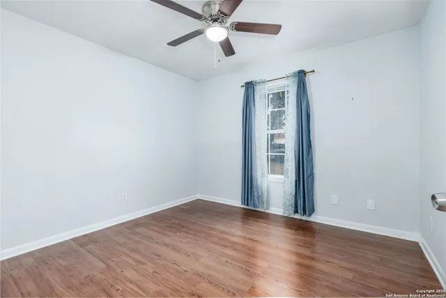 a view of empty room with wooden floor and ceiling fan