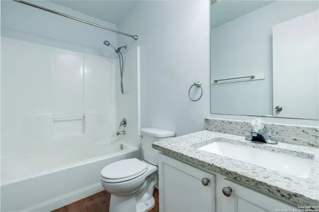 a bathroom with a granite countertop toilet sink and mirror