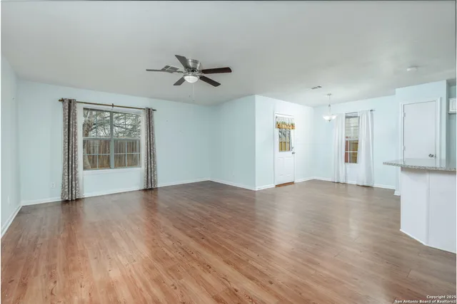 a view of empty room with wooden floor and fan