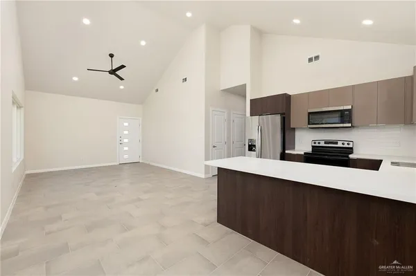 a large kitchen with stainless steel appliances a large counter top a stove a sink and a refrigerator