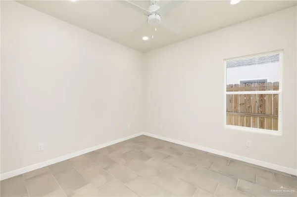 an empty room with a windows and chandelier fan