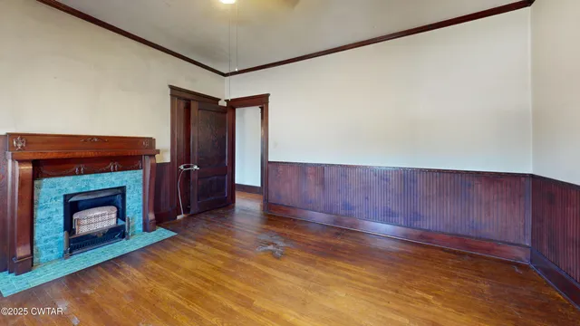 a view of an empty room with wooden floor and a fireplace