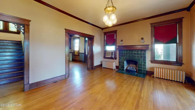 a view of an empty room with wooden floor fireplace and a window