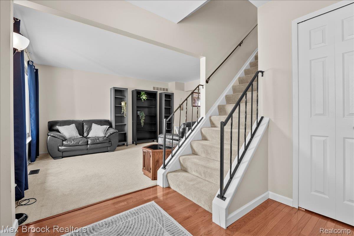 42470 Bishop Road Canton, MI 48188 - Photo 4 of 37 Open-concept living area featuring hardwood flooring, a curved staircase with metal railings, and abundant natural light from multiple windows